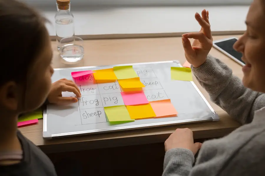 Child and speech therapist using word cards and gestures to support communication
